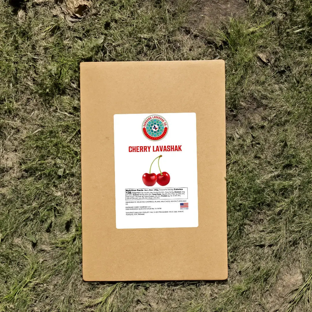 Darband Sour Cherry Lavashak kraft paper packaging displayed outdoors on natural grass — authentic traditional Persian fruit leather made in the USA with real cherries