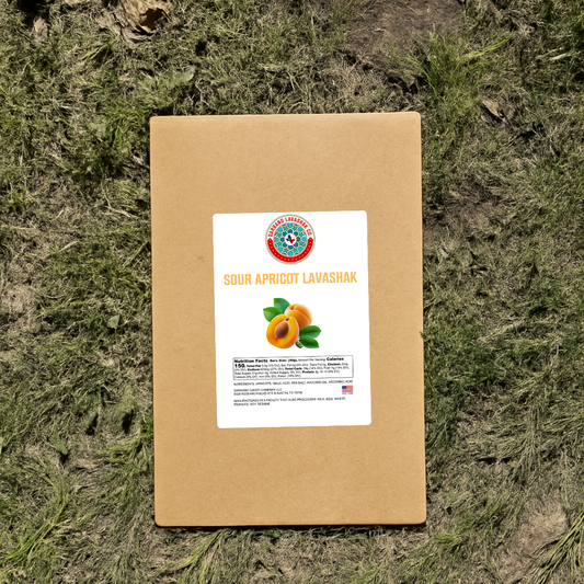 Darband Sour Apricot Lavashak kraft box packaging displayed outdoors on natural grass — authentic traditional Persian fruit leather made in the USA with real apricots
